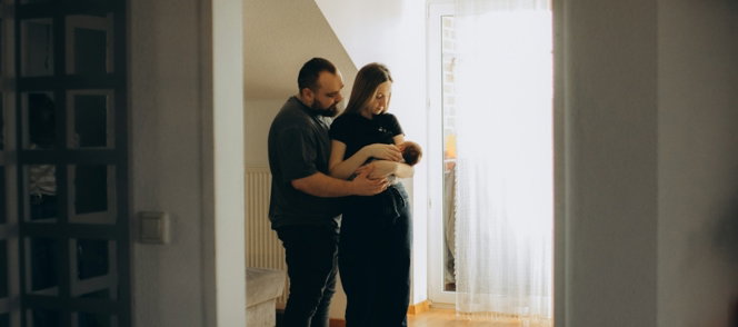 Parents holding their newborn baby indoors.